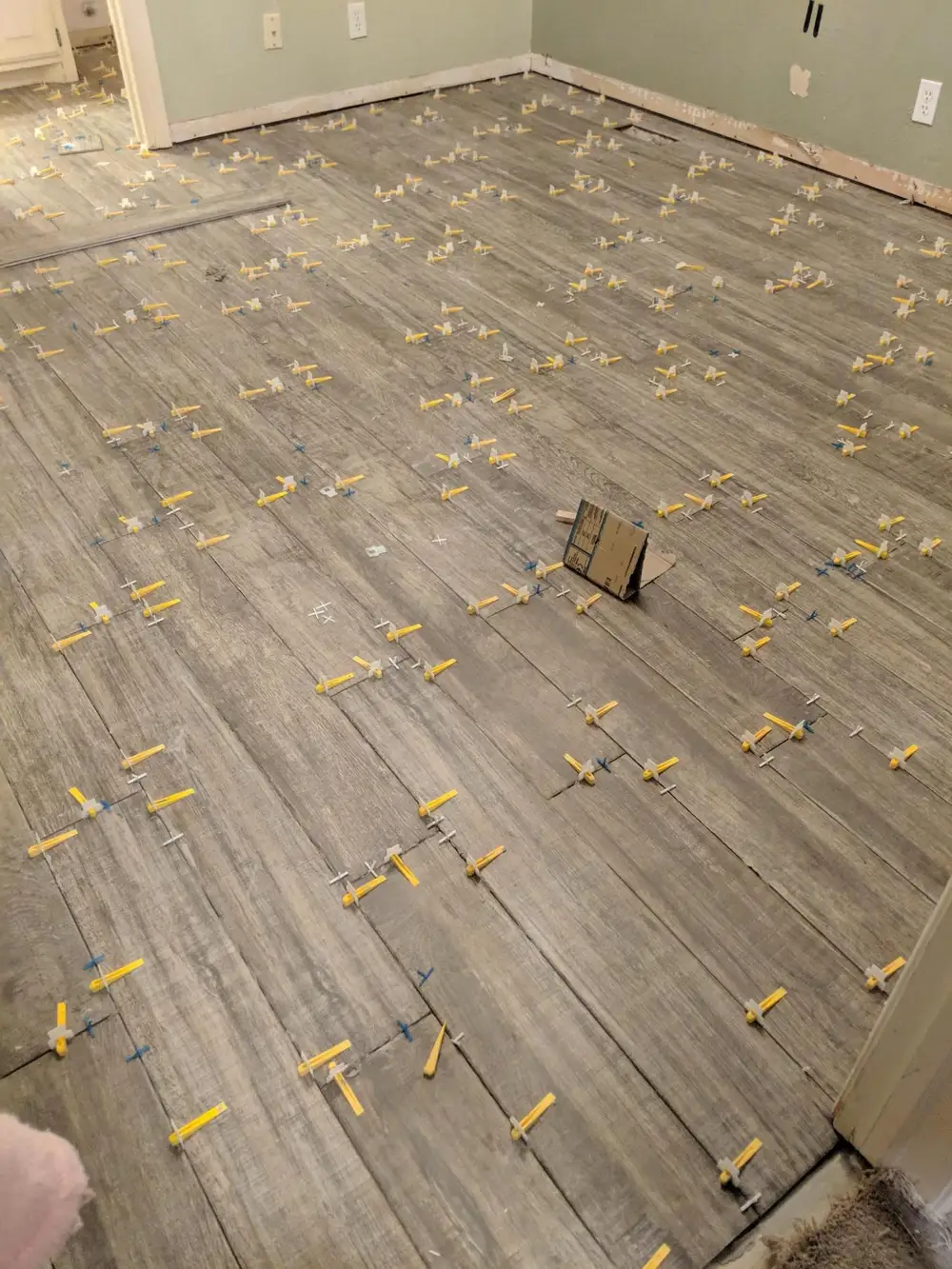 Wood-look tile part-laid with levelling clips across the floor on a J-Mar installation